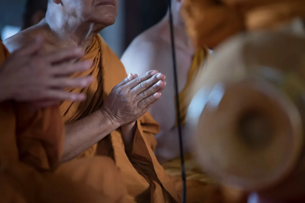 A monk with praying hands during a meditation session in Thailand