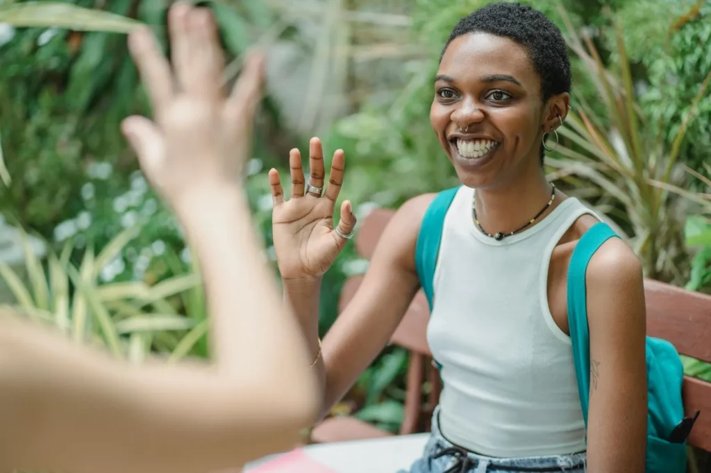 A woman waving and smiling at another person in front of her