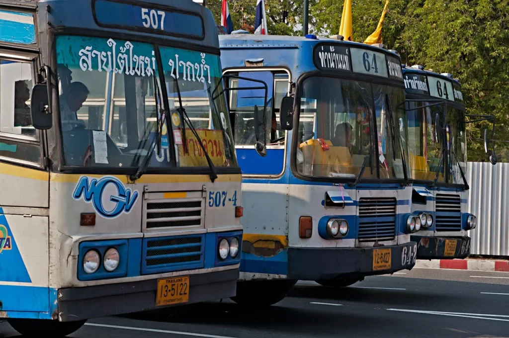 Three blue and white buses labelled with different routes in Bangkok