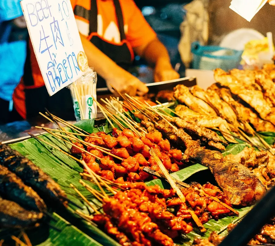 An array of different skewered meats displayed on top of banana leaves served at the street food markets in Chiang Mai