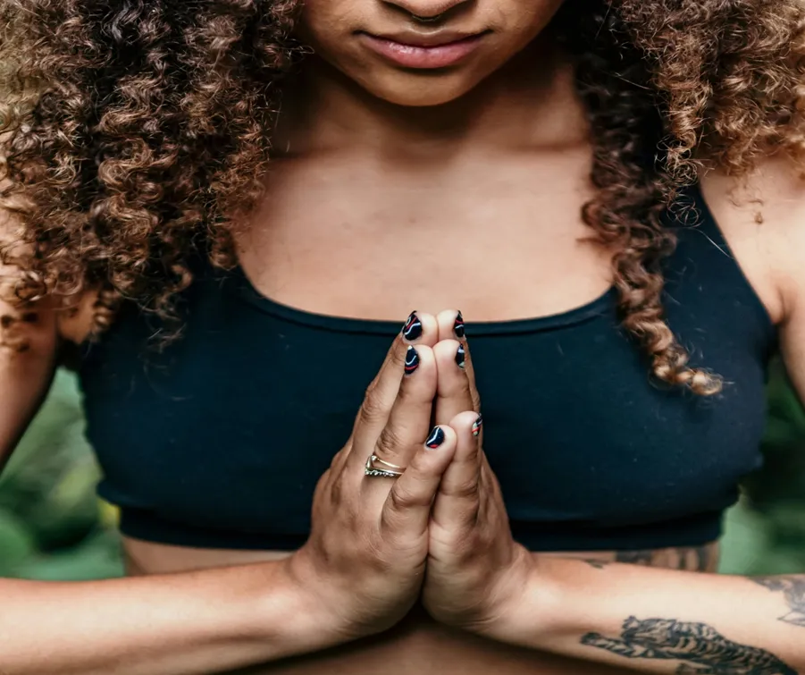 A woman showing respect by tilting her head down and her palms together on her chest

